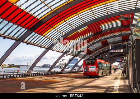 AMSTERDAM, NETHERLANDS - SEPTEMBER 1, 2018: Central Station in Amsterdam bus platform with colorful overhang seen with boats and buildings visible Stock Photo