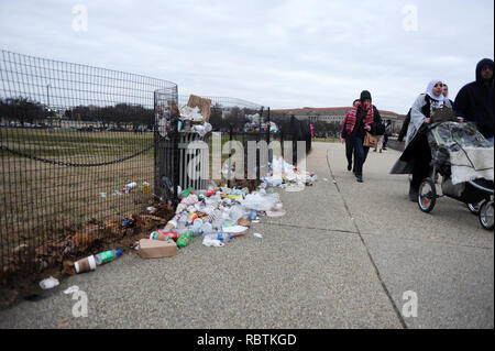 People walk by trash uncollected on the National Mall in Washington DC on the 12th day of the partial government shutdown Jan. 2, 2019. Stock Photo