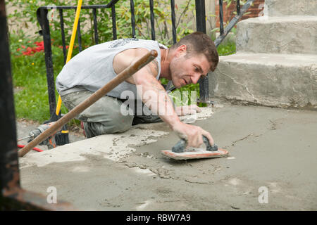 Workman smooths  a skim coating of cement on old stairway.