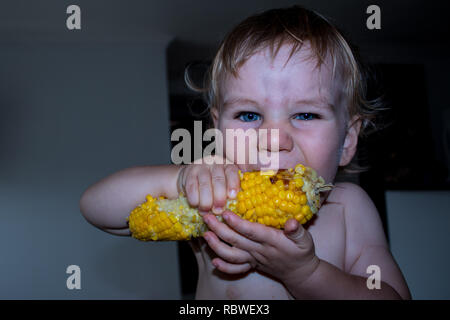 A photo of a little boy eating and enjoying maize (corn) Stock Photo