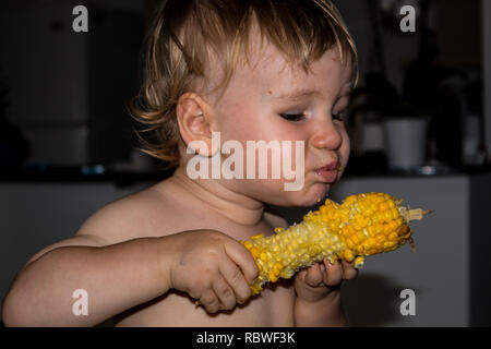 A photo of a little boy eating and enjoying maize (corn) Stock Photo