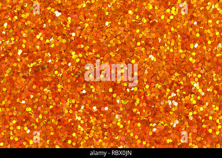 Orange glittering foil leaf shiny wrapping paper glitter texture background for Christmas holiday. Stock Photo