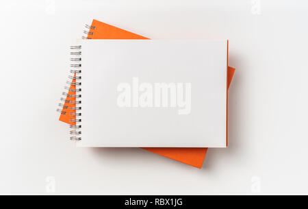 Design concept - Top view of 2 orange spiral notebook, white page isolated on background for mockup Stock Photo