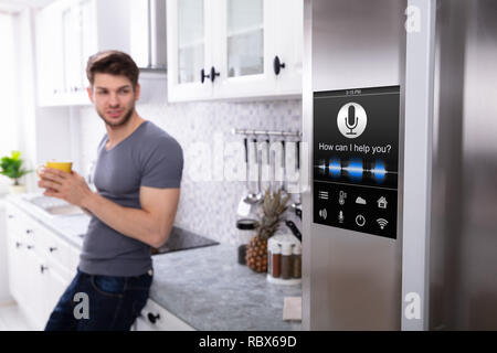 Man Standing Near Oven With Voice Recognition Function In Kitchen Stock Photo