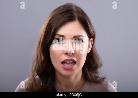 Portrait Of A Sad Young Woman On Grey Background Stock Photo