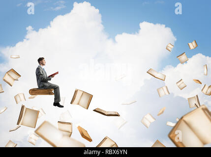 Man reading book and many of them flying in air Stock Photo