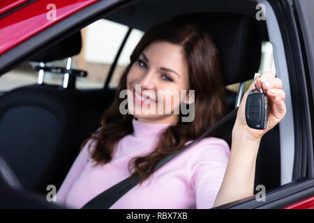 Close-up Of A Happy Young Woman Sitting Inside Car Showing Key Stock Photo