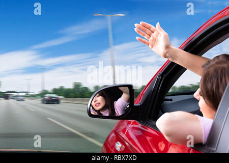 Young Woman Making Gesture While Looking Out Of Car Window Stock Photo