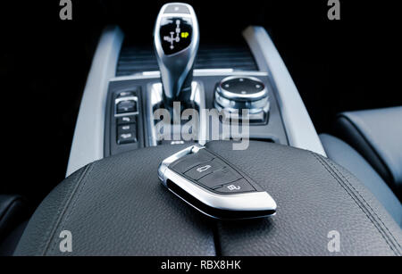 Closeup inside vehicle of wireless key ignition. Start engine key. Car key remote in black perforated leather interior. Modern car background. Modern  Stock Photo