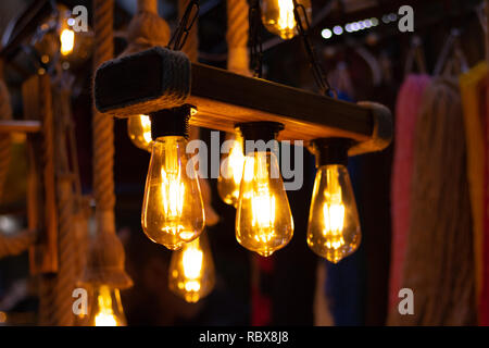Light bulbs hanging on the wooden stand in the shop for sale. Stock Photo