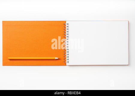 Design concept - Top view of orange spiral notebook, white page and pencil isolated on background for mockup Stock Photo