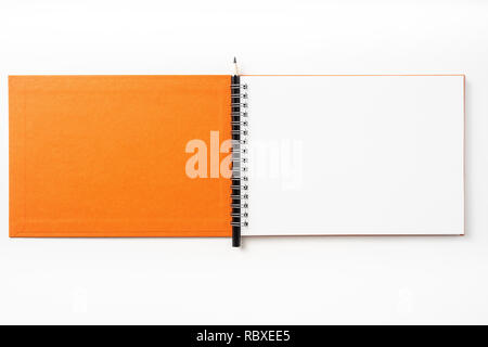 Design concept - Top view of orange spiral notebook, white page and pencil isolated on background for mockup Stock Photo