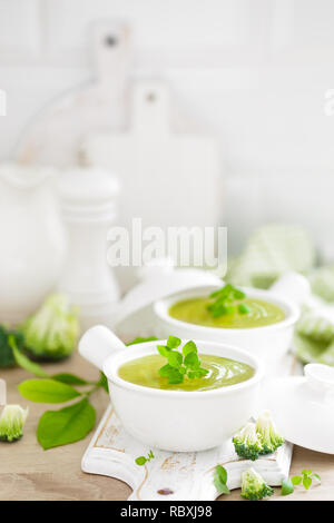 Broccoli soup in bowls on wooden kitchen table closeup. Healthy vegetarian dish. Diet food Stock Photo