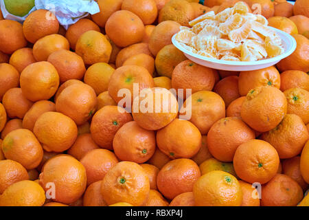 Tangerines for sale at a market with some pieces on a plate Stock Photo