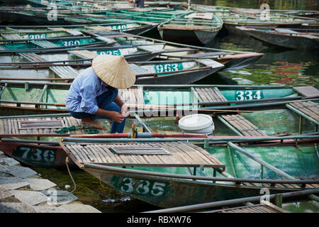 Vietnamese man with hat working in a boat, in Tam Coc harbour, in Ninh Binh, Vietnam Stock Photo