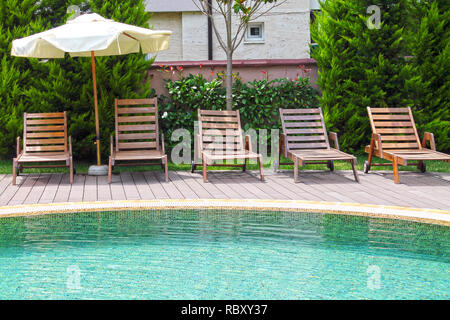 Swimming pool with lounges and parasol. Stock Photo