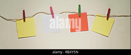 Orange, yellow and white paper stickers with clothespins on a rope Stock Photo