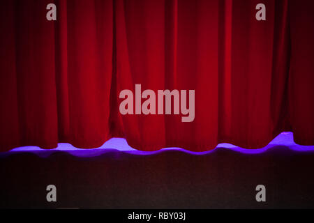 Red curtain backdrop on theatre stage with soft lighting. Stock Photo