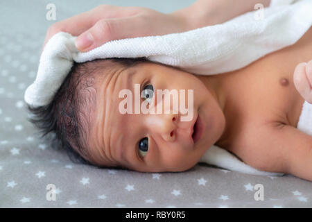 asian baby boy smiling and feeling happy after taking bath. mother dries and rubs her newborn baby hair and head with a towel after taking a shower. f