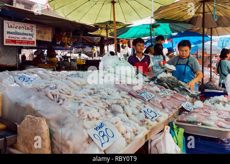 Samut Sakhon, Thailand - October 29, 2018 :  asian fishmonger preparing and pouring the ice on river shrimp, squid and other seafood to sell in stall  Stock Photo