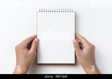 Design concept - Top view of brown spiral notebook, white page and pencil, man hold notebook on background for mockup Stock Photo