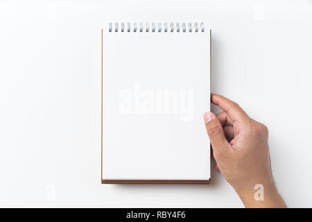 Design concept - Top view of brown spiral notebook, white page and pencil, man hold notebook on background for mockup Stock Photo