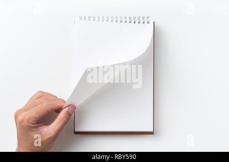 Design concept - Perspective view brown hardcover spiral notebook, man's hand flip curl page isolated on background for mockup Stock Photo