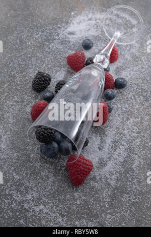 Fresh berries and champagne glass on a plate of granite whith sugar  - Imagen