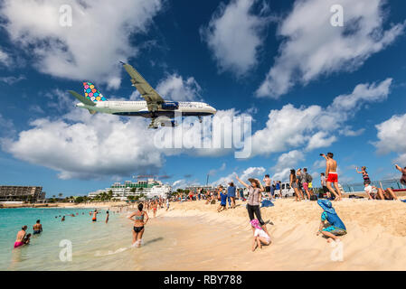 Maho beach, Saint Martin - December 17, 2018: A commercial jet approaches Princess Juliana airport above onlooking spectators. The short runway gives  Stock Photo