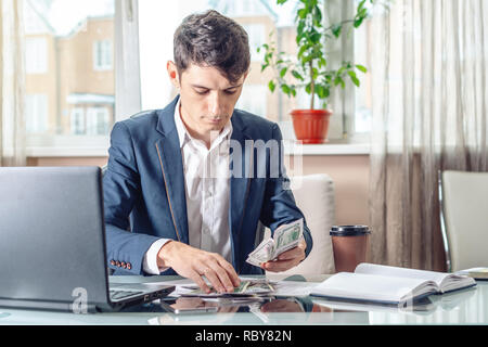 Businessman official sitting in the workplace in the office takes a bribe with his hands counting the money. The concept of corruption and bribery Stock Photo