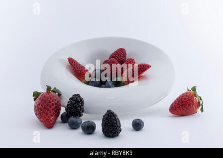 Fresh berries  on a white dish on a white background.  - Imagen