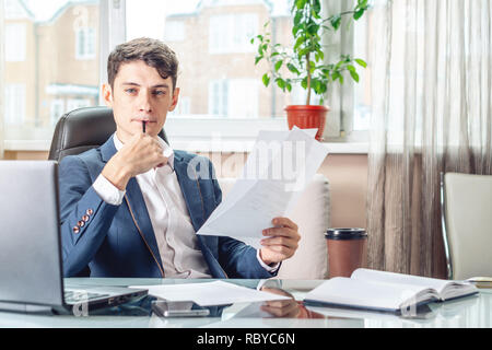 Male Manager sitting at a work place examing documents. The concept of the office working with documents Stock Photo