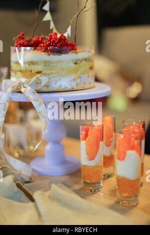 Delicious yummy cake with red viburnum on and drinks. Concept of sweets for birthday party and dessert. Stock Photo