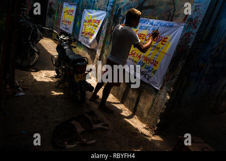 A Colombian sign painter writes with a brush while working on music party posters in the sign painting workshop in Cartagena, Colombia. Stock Photo