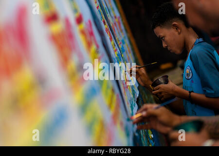 A Colombian sign painter apprentice writes with a brush while working on music party posters in the sign painting workshop in Cartagena, Colombia. Stock Photo