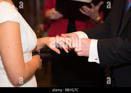 Wedding rings. Wedding day. Hands of bride and groom in solemn process of exchanging rings, symbolizing the creation of new happy family. Stock Photo