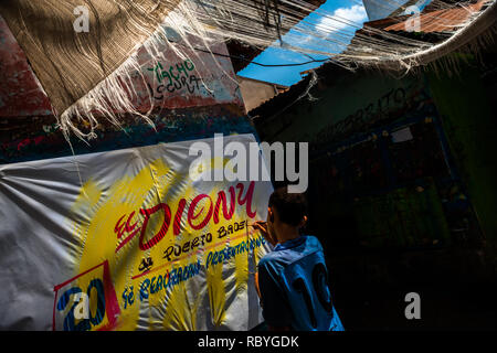 A Colombian sign painter apprentice writes with a brush while working on music party posters in the sign painting workshop in Cartagena, Colombia. Stock Photo