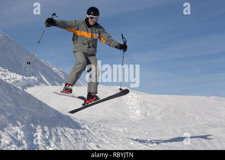 Amateur male skier jumping from side of small slope in French ski resort. Stock Photo