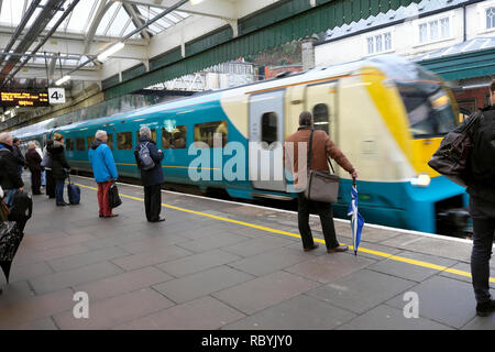 Shrewsbury train station a moving train approaching people waiting on platform waiting to get on to travel to Manchester UK England KATHY DEWITT Stock Photo