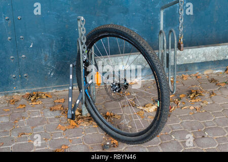 Berlin, Germany - April 02, 2018: Sad residue: After a theft, only one wheel is left. But this is at least secured by a bicycle lock on the bicycle st Stock Photo