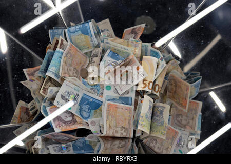 A pile of British sterling paper and polymer money £5 and £10 bank notes in a collection box  with light reflections in London UK  KATHY DEWITT Stock Photo