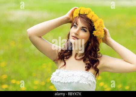 beautiful girl with dandelion flowers in green field Stock Photo