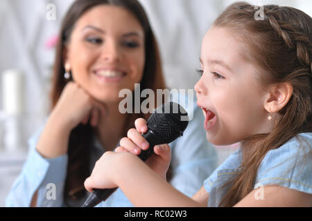 Portrait of little girl with mother singing karaoke Stock Photo