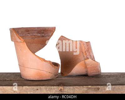 A broken terracotta flowerpot on old box, isolated on white bhind. Frost damage. Stock Photo