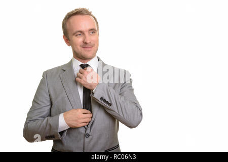 Handsome Caucasian businessman fixing his tie isolated against white background Stock Photo