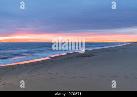 Sunrise along the Atlantic Ocean in Virginia Beach at Little Island Park in Sandbridge.  The sun creates pink and purple pastel reflections on the sur Stock Photo