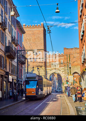 A tram crossing Corso di Porta Ticinese street with the Antica Porta Ticinese in the background. Milan, Lombardy, Italy. Stock Photo