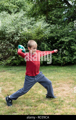 Ten year old boy throwing a football in his yard. (MR) Stock Photo