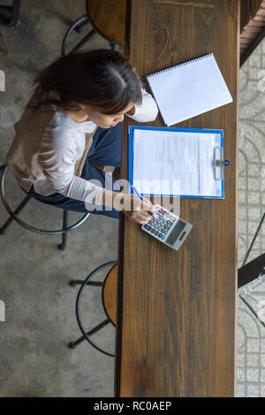 Asian woman using calculator to check her calculation Stock Photo