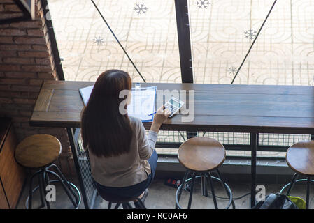 Checking the price on reports with calculator Stock Photo